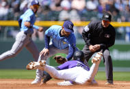 Tampa Bay Rays second base Brandon Lowe, center, tags out Colorado Rockies' Nolan Jones, front, as he tries to steal second base as umpire Nick Mahrley waits to make the call in the second inning of a baseball game Sunday, April 7, 2024, in Denver. (AP Photo/David Zalubowski)