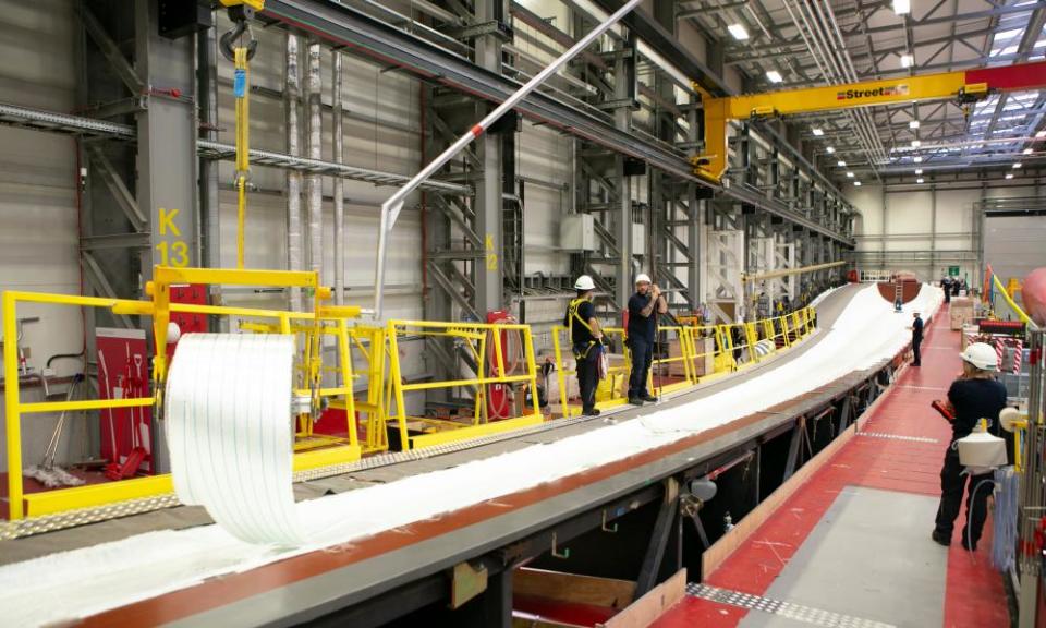 Workers at the Siemens Gamesa factory unroll layers of fibreglass and balsa wood into 81-metre moulds, before resins and paint are added.