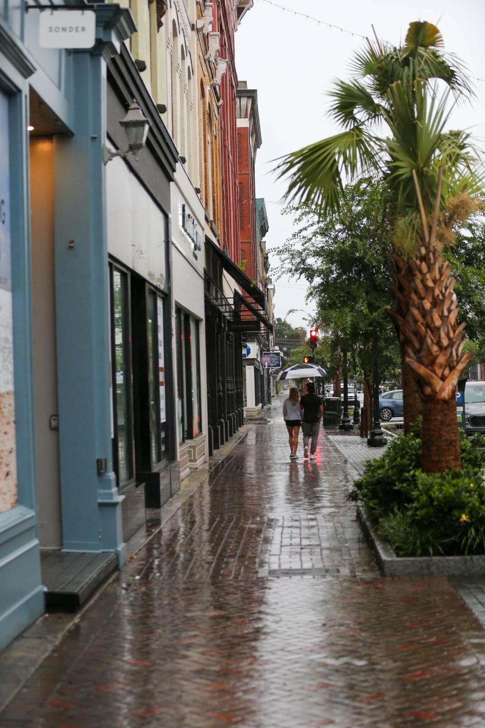 Visitors cover up with an umbrella as they walk along Broughton Street on Wednesday, August 30, 2023 as Hurricane Idalia made landfall in Florida.