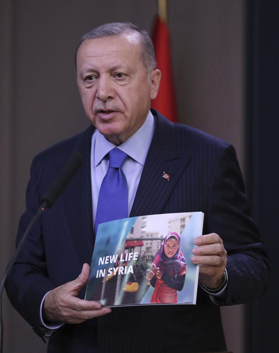 Turkish President Recep Tayyip Erdogan shows a document as he speaks to reporters before a visit to the United States, in Ankara, Turkey, Tuesday, Nov. 12, 2019. Erdogan warned European nations Tuesday that his country could release all the Islamic State group prisoners it holds and send them to Europe, in response to EU sanctions over Cyprus.(Presidential Press Service via AP, Pool)