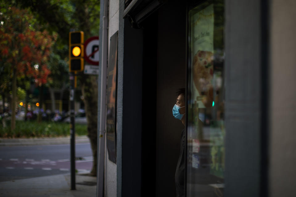 In this Sunday, May 31, 2020 photo, a waiter wearing a face mask waits for customers in a terrace bar in Barcelona. Spain's national statistics office said that it received zero international tourists in April after the nation had closed its borders at the height of its coronavirus outbreak. (AP Photo/Emilio Morenatti)