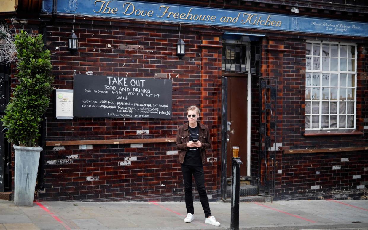 A customer buys a takeaway draught beer from a pub in Broadway Market, London - AFP