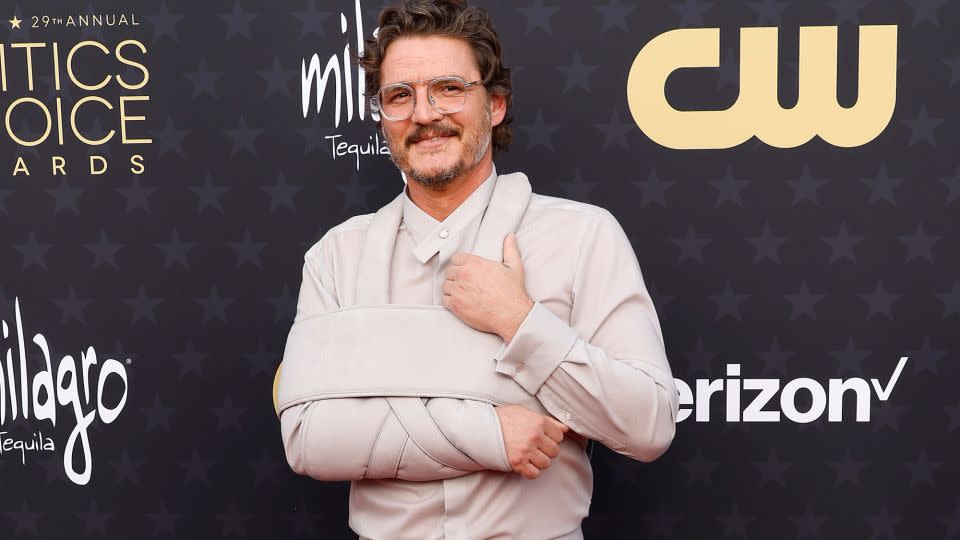 As at last week’s Golden Globes, Pedro Pascal incorporated his arm sling into his look — this time, a gray-beige outfit paired with clear spectacles and black shoes. - Frazer Harrison/Getty Images