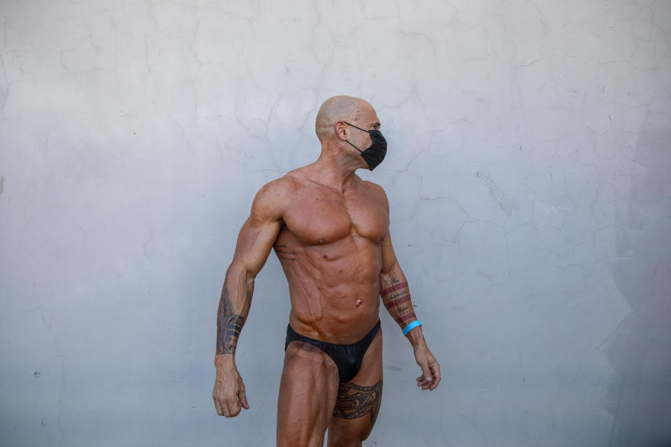 A contestant wearing protective face mask exercises backstage during the National Amateur Body Builders Association competition in Tel Aviv, Israel, Wednesday, Aug. 19, 2020. Because of the coronavirus pandemic, this year's competition was staged outdoors in Tel Aviv. The 85 participants were required to don protective masks in line with health codes. (AP Photo/Oded Balilty)