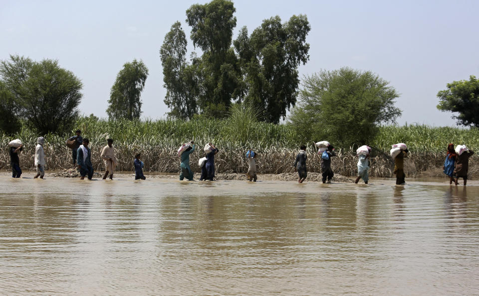 Victims of unprecedented flooding from monsoon rains receive relief aid organized by the Edhi Foundation, in the Ghotki District of Sindh Pakistan, Wednesday, Sept. 7, 2022. (AP Photo/Fareed Khan)