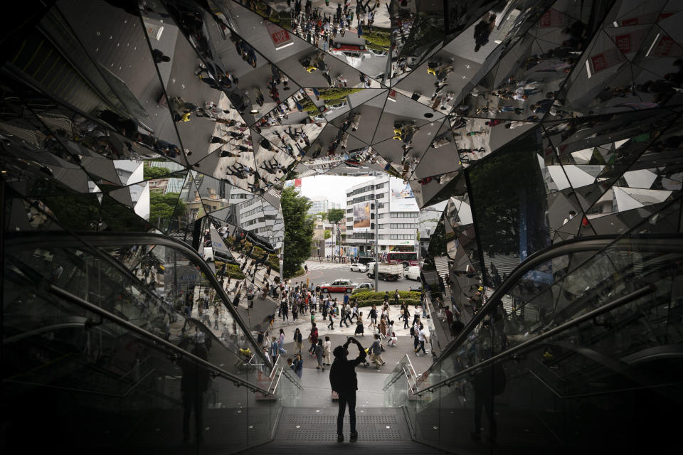 A man takes pictures in the entrance way to a shopping mall decorated with mirrors Saturday, May 18, 2019, in Harajuku district of Tokyo. (AP Photo/Jae C. Hong)