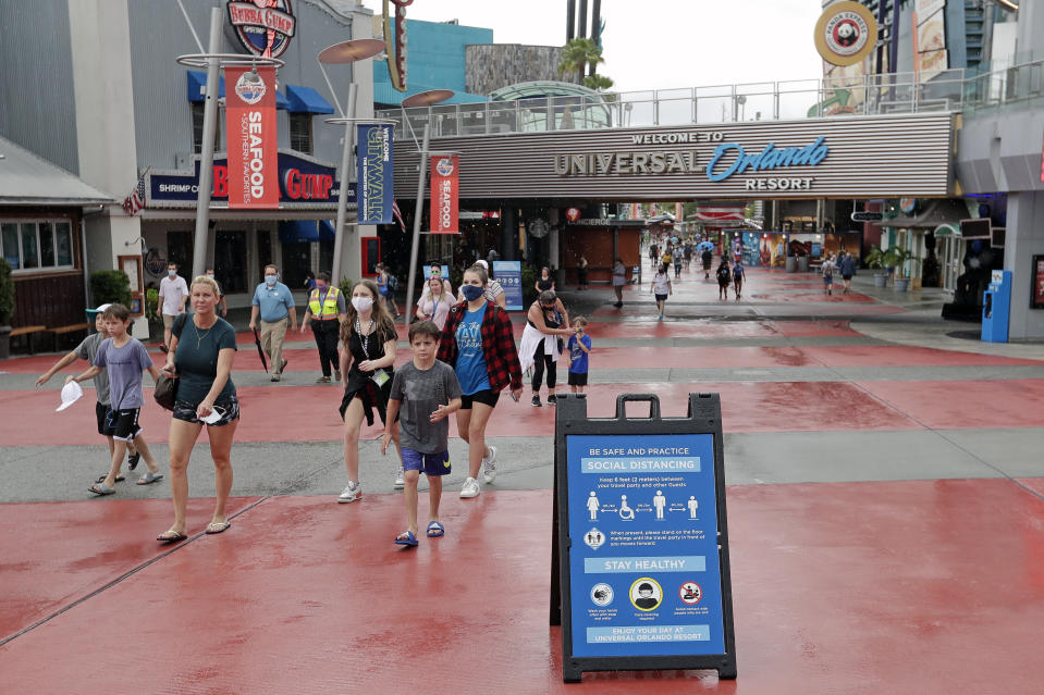 En esta foto del miércoles 3 de junio de 2020, carteles sobre el distanciamiento social y otros protocolos reciben a los visitantes del Universal Orlando Resort en Orlando, Florida. El parque temático reabrió sus puertas para aquellas personas con pases de temporada y abrirá al público general el viernes. (AP Foto/John Raoux)