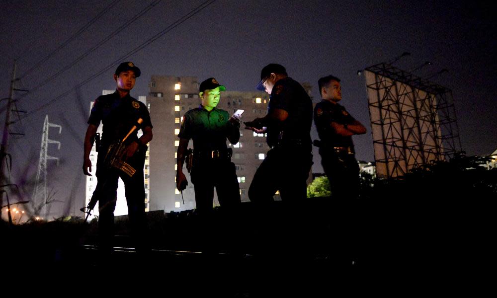 Police officers stand guard near a crime scene where a suspected drug pusher was shot dead in Manila.