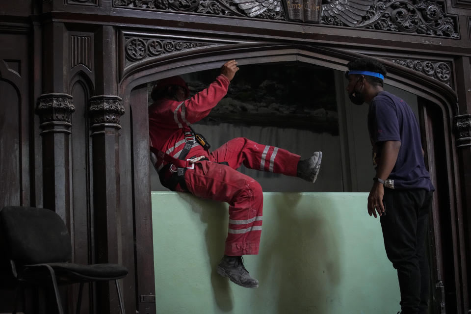 A member of the Cuban Red Cross jumps a wall as he leaves the Calvary Baptist Church, in Old Havana, Cuba, Wednesday, May 11, 2022. The May 6th explosion that devastated the Hotel Saratoga and killed dozens also badly damaged Cuba's most important Baptist church, which sits next door. (AP Photo/Ramon Espinosa)