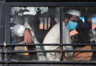 Men wearing protective masks sit inside a bus that will take them to a quarantine facility, amid concerns about the spread of coronavirus disease (COVID-19), in Nizamuddin area of New Delhi