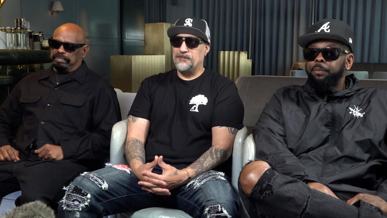 Cypress Hill in black outfits sitting in a hotel bar