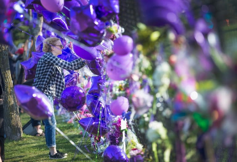 A fan visits a memorial created outside Paisley Park, the home and studio of Prince, on April 23, 2016 in Chanhassen, Minnesota