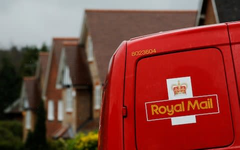 A Royal Mail postal van is parked outside homes in Maybury near Woking in southern England - Credit: Luke MacGregor/Reuters