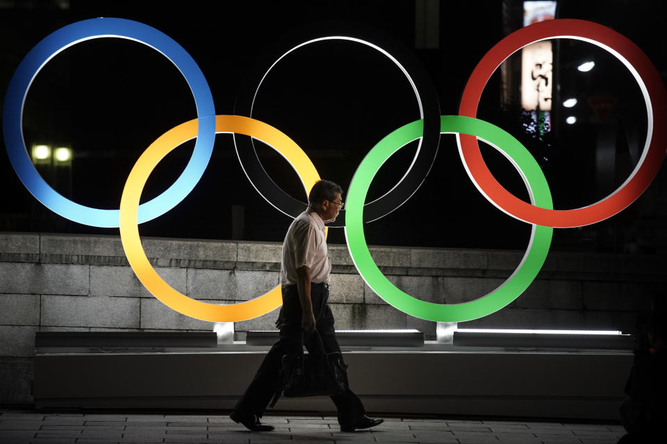 A man walks past the Olympic rings Tuesday, July 23, 2019, in Tokyo, as Japan marks a year-to-go until hosting the summer games with Olympic medals being unveiled Wednesday as part of daylong ceremonies around the Japanese capital. The Summer Olympics will return to Tokyo next year for the first time since 1964. (AP Photo/Jae C. Hong)