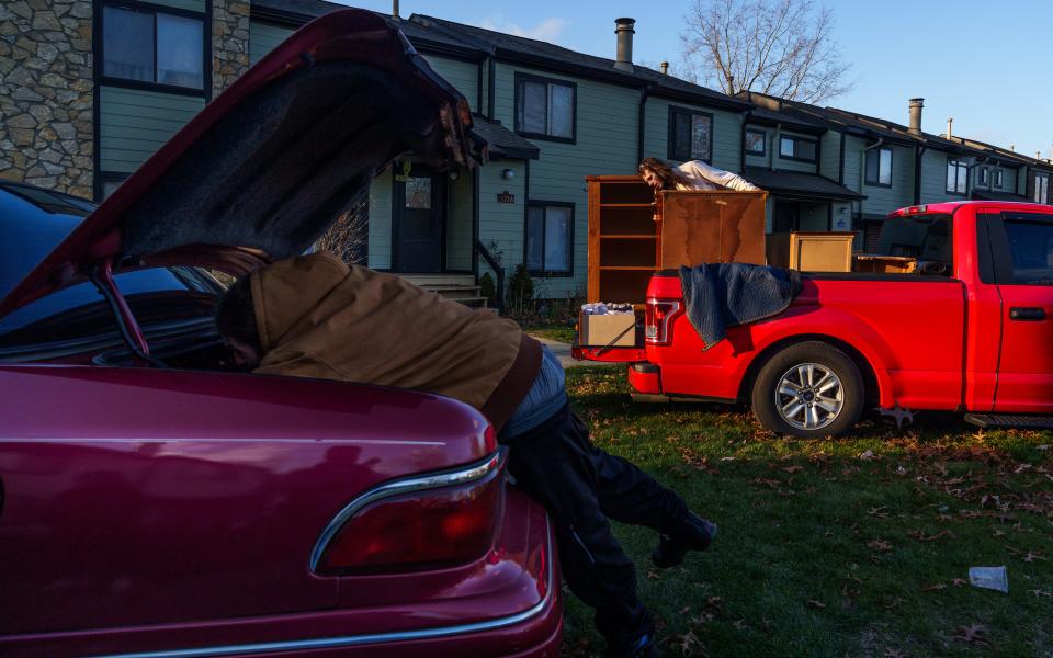 Austin Jensen fills a car trunk with his and his friend Reeda Raney's belongings Monday, Nov. 27, 2023, as his friend Dillon rearranges furniture in the bed of a borrowed truck. Jensen and Raney are moving everything into storage after being evicted from their north west side apartment after falling behind in rent.