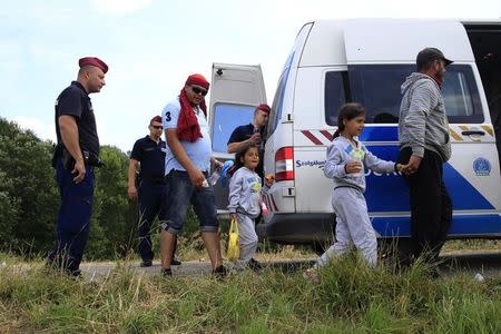 Police escort migrants from Syria into a police van, after they crossed the border from Serbia to Hungary, walking on the dam near the Tisza river near the city of Szeged, Hungary, on June 29, 2015. REUTERS/Bernadett Szabo - RTX1I97P