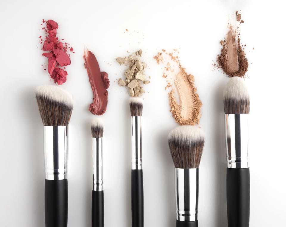 Creative concept beauty fashion photo of cosmetic product make up brushes kit with smashed lipstick eyeshadow on white background.