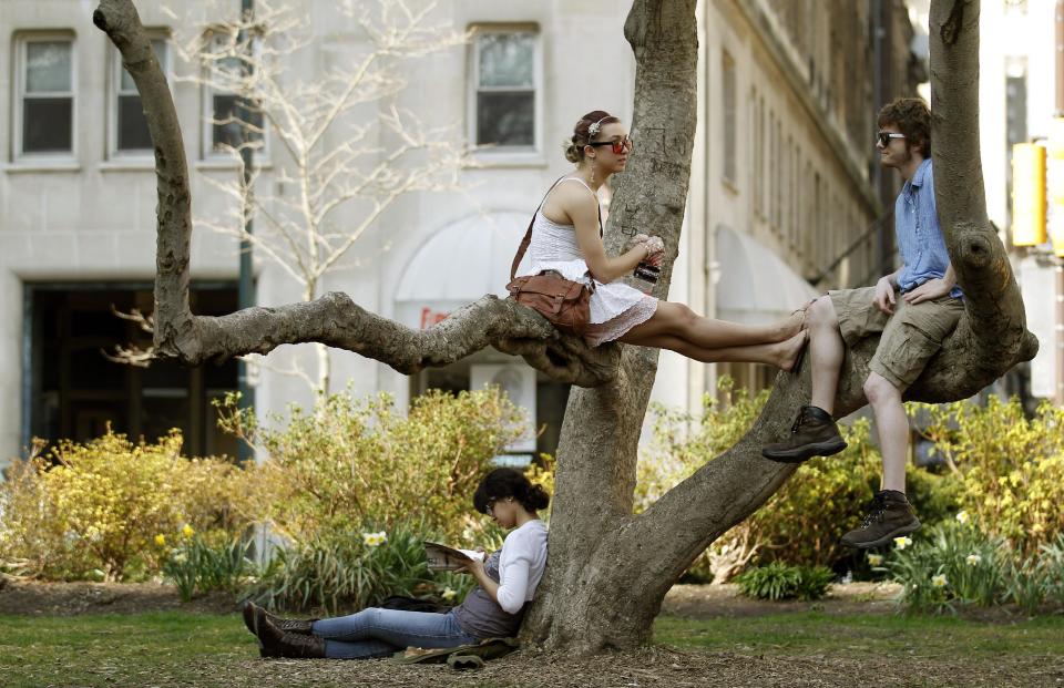 Amanda Diaz, bottom left, reads a book as Ciara Perez, top left, and Chris Elam sit in a tree during the unseasonably warm weather in the Rittenhouse Square park Tuesday, March 13, 2012 in Philadelphia. (AP Photo/Alex Brandon)