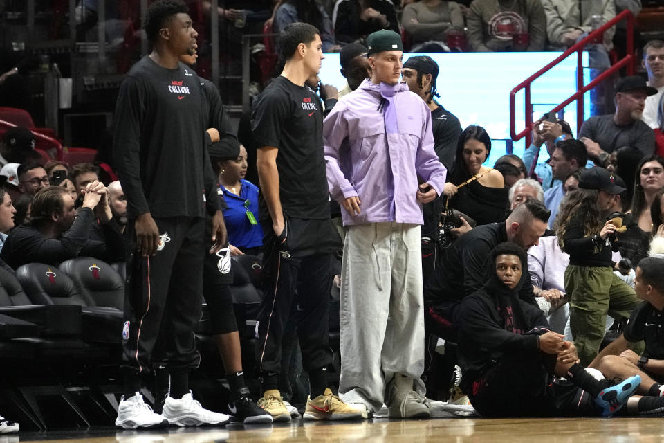 Miami Heat guard Tyler Herro, right, watches from the sideline during the second half of an NBA basketball game against the Charlotte Hornets, Wednesday, Dec. 13, 2023, in Miami. (AP Photo/Lynne Sladky)