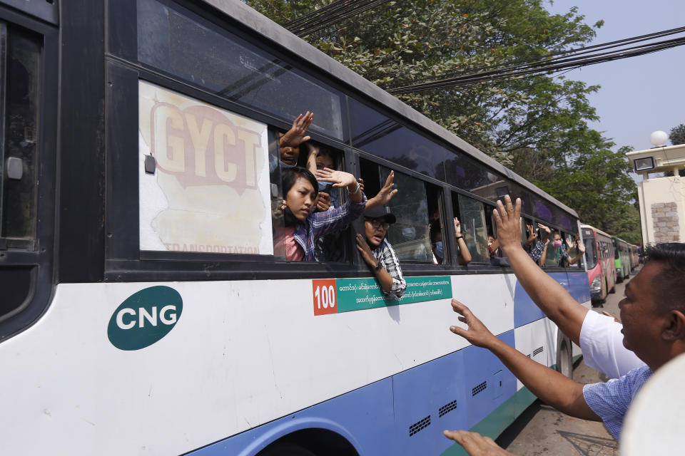 Arrested protesters wave to people while onboard a bus that is part of a convoy of buses getting out of Insein prison and will transport them to an undisclosed location Wednesday, March 24, 2021 in Yangon, Myanmar. (AP Photo)
