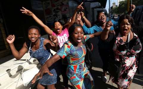 Zimbabweans celebrate in the morning sun after President Mugabe resigned in Harare - Credit: MIKE HUTCHINGS/ REUTERS