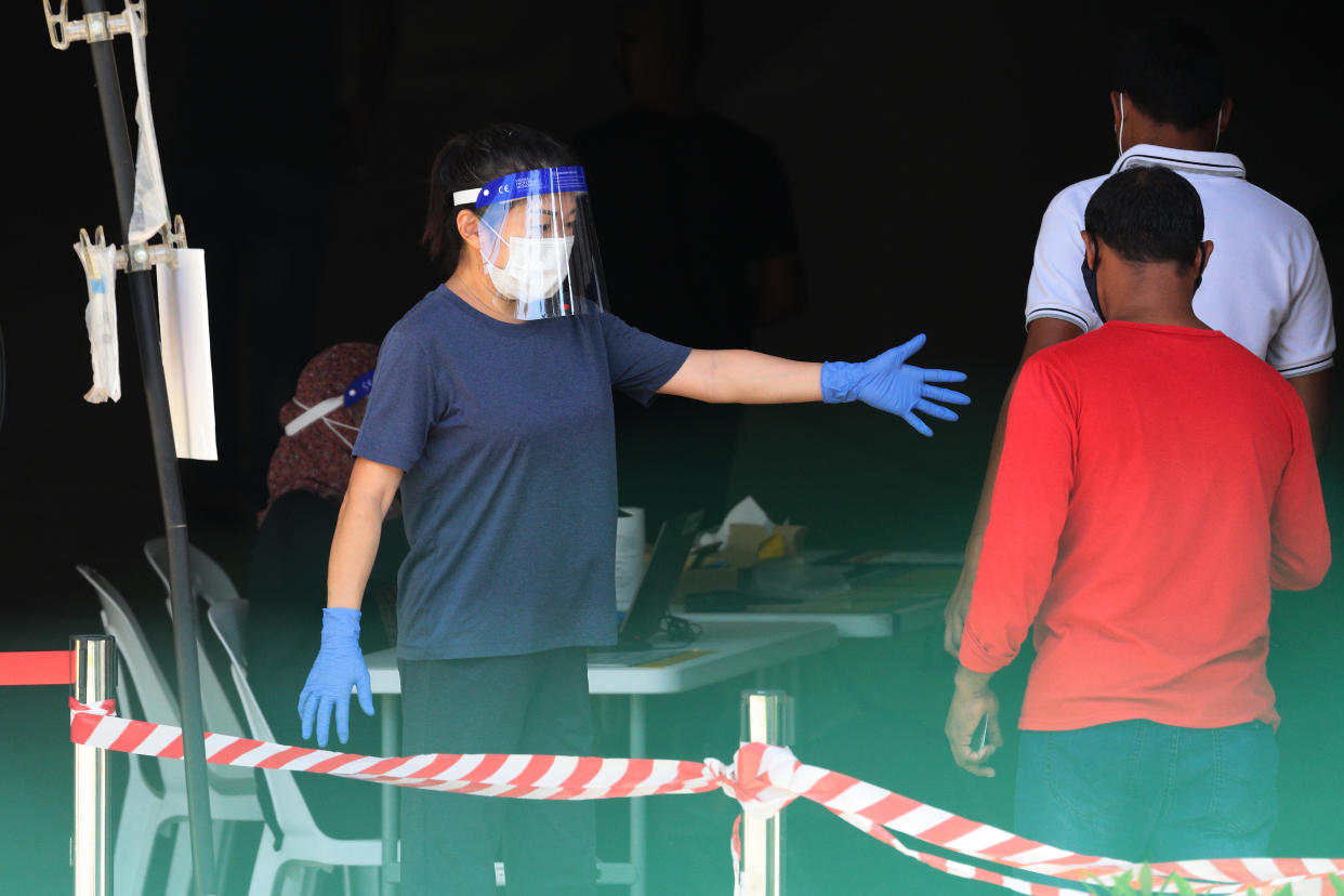 An officer wearing gloves, face shield and protective mask directs the migrant workers in queue to enter a Regional Screening Centre to undergo Rostered Routine Testing (RRT) swab on October 9, 2021 in Singapore. RRT is a surveillance training program for targetted groups who are vulnerable and have higher risk of exposure to COVID-19 which involves recurrent swab testing every 14 days. (Photo by Suhaimi Abdullah/NurPhoto via Getty Images)