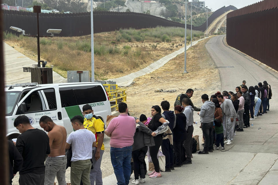 FILE - Migrants seeking asylum line up while waiting to be processed after crossing the border June 5, 2024, in San Diego, Calif. Over the course of two weeks, President Joe Biden has imposed significant restrictions on immigrants seeking asylum in the U.S. and then offered potential citizenship to hundreds of thousands of people without legal status already living in the country. The two actions in tandem gives the president a chance to address one of the biggest vulnerabilities for his reelection campaign. (AP Photo/Eugene Garcia, File)