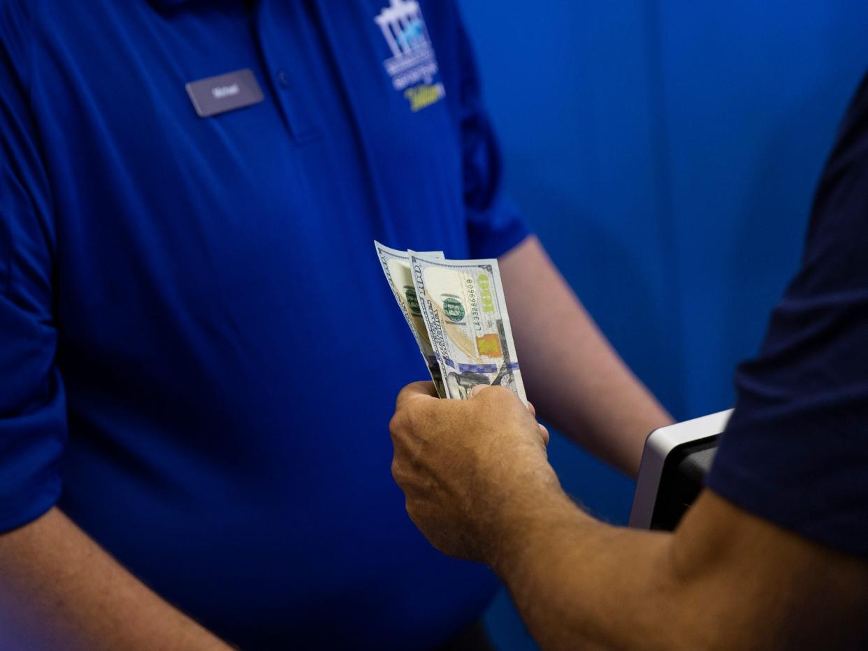 A bettor hands cash to a teller on June 14, 2018 to place a bet at the Monmouth Park Sports Book on the first day of legal sports betting in the state, in Monmouth Park in Oceanport, New Jersey.