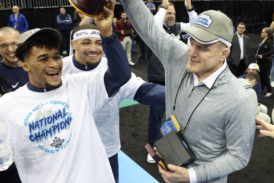 Penn State wrestling’s Carter Starocci and coach Cael Sanderson celebrate Saturday after winning the team championship at the T-Mobile Center.