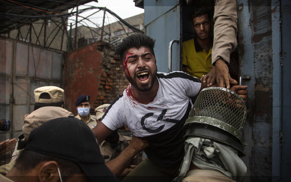 Indian policemen detain a Kashmiri Shiite Muslim as he attempt with others to take out a religious procession in Srinagar, Indian controlled Kashmir, Friday, Aug. 28, 2020. Police and paramilitary soldiers on Friday detain dozens of Muslims participating in religious processions in the Indian portion of Kashmir. Authorities had imposed restrictions in parts of Srinagar, the region's main city, to prevent gatherings marking Muharram from developing into anti-India protests. (AP Photo/Mukhtar Khan)