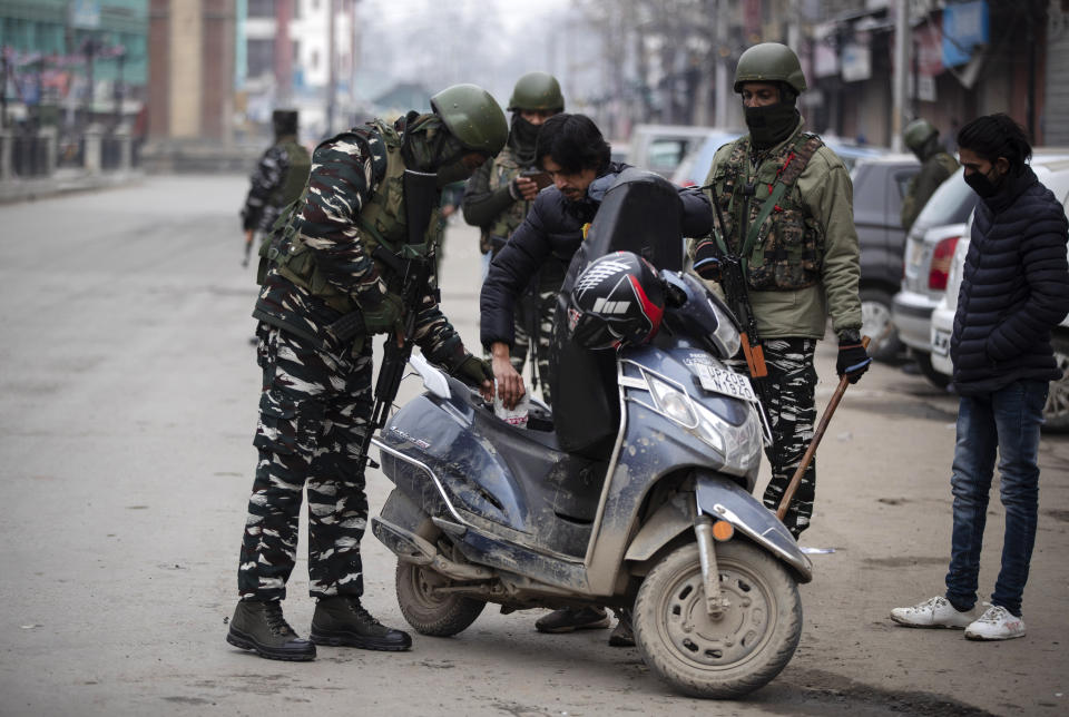 Indian paramilitary soldiers check a scooter of a Kashmiri man in Srinagar, Indian controlled Kashmir, Tuesday, Feb. 9, 2021. Businesses and shops have closed in many parts of Indian-controlled Kashmir to mark the eighth anniversary of the secret execution of a Kashmiri man in New Delhi. Hundreds of armed police and paramilitary soldiers in riot gear patrolled as most residents stayed indoors in the disputed region’s main city of Srinagar. (AP Photo/Mukhtar Khan)