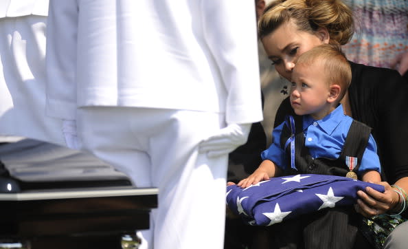 The U.S. Navy Color Guard presents the flag that adorned the casket of Jonathan Blunk to his son Maximus Blunk, 2, sitting on the lap of his mother Chantel Blunk at Mountain View Cemetery August 03, 2012, in Reno, Nevada. Blunk, a five-year U.S. Navy veteran, was killed in the July 20 shooting rampage at a movie theater in Aurora Colorado. (Photo by RJ Sangosti-Pool/Getty Images)