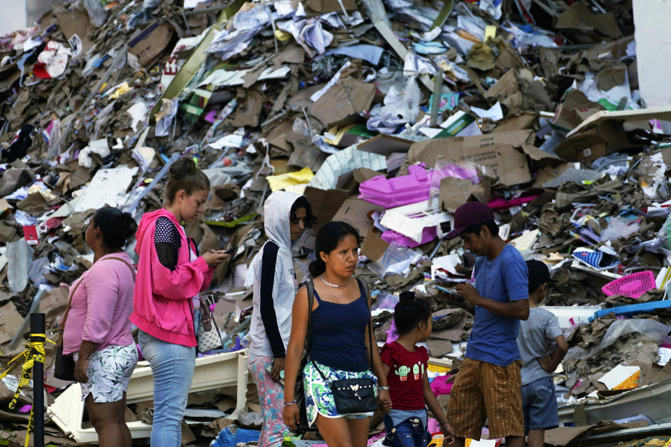 Residentes caminan al lado de una montaña de basura tras la devastación que dejó el paso del huracán Otis, en Acapulco, México, el domingo 12 de noviembre de 2023. Cerca de tres semanas después de que el ciclón de categoría 5 destrozara el puerto del océano Pacífico, dejando 48 personas muertas y la infraestructura de la ciudad hecha pedazos, las tareas de limpieza siguen pendientes. (AP Foto/Marco Ugarte)