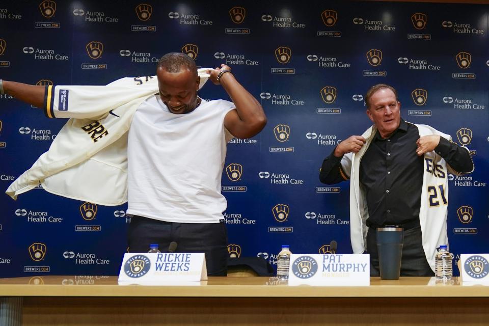 Pat Murphy and associate manager Rickie Weeks, left put on jersey's at a news conference where he was named Milwaukee Brewers baseball team manager Thursday, Nov. 16, 2023, in Milwaukee. (AP Photo/Morry Gash)