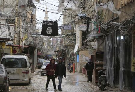 Youth walk under an Islamic State flag in Ain al-Hilweh Palestinian refugee camp, near the port-city of Sidon, southern Lebanon January 19, 2016. REUTERS/Ali Hashisho/Files