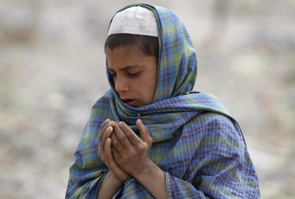 An Afghan boy prays over the grave of one of the sixteen victims killed in a shooting rampage in the Panjwai district of Kandahar province south of Kabul, Afghanistan, Saturday, March 24, 2012. Mohammad Wazir has trouble even drinking water now, because it reminds him of the last time he saw his seven-year-old daughter. He had asked his wife for a drink but his daughter insisted on fetching it. Now his daughter Masooma is dead, killed along with 10 other members of his family in a shooting rampage attributed to a U.S. soldier. The soldier faces the death penalty but Wazir and his neighbors say they feel irreparably broken. (AP Photo/Allauddin Khan)