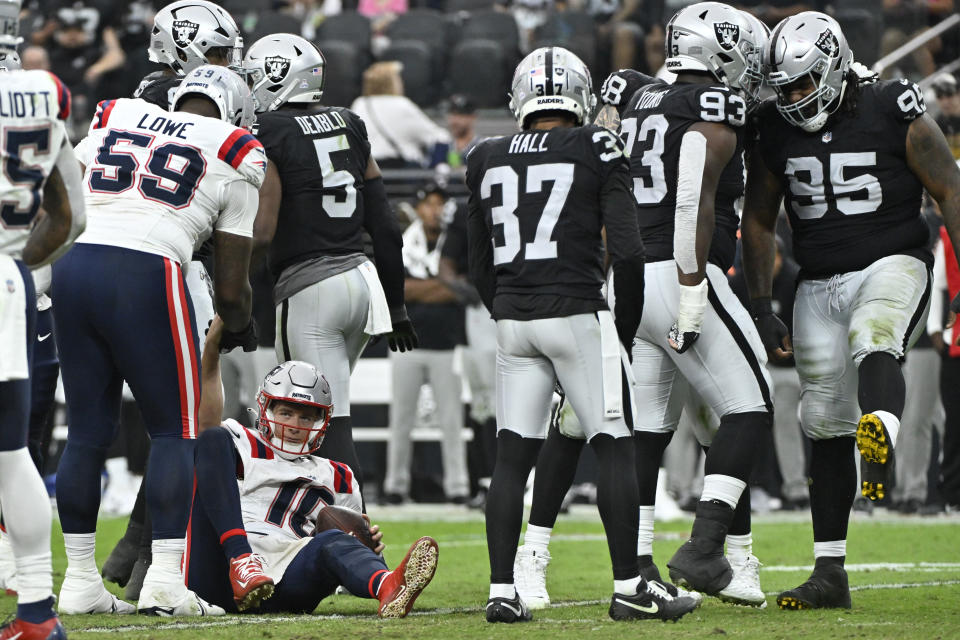 New England Patriots quarterback Mac Jones, below left, is helped up after being sacked by Las Vegas Raiders defensive tackle John Jenkins, right, during the second half of an NFL football game Sunday, Oct. 15, 2023, in Las Vegas. (AP Photo/David Becker)