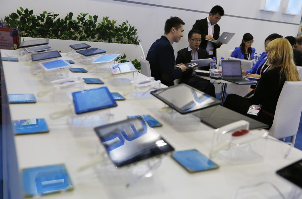 In this April 12, 2014 photo, a potential buyer, left, studies the Chinese made tablets in a booth at the Global Sources Spring China Sourcing Fair in Hong Kong. As China's economy downshifts, manufacturers are bracing for the turning point that’s in store for the world’s second biggest economy. (AP Photo/Kin Cheung)