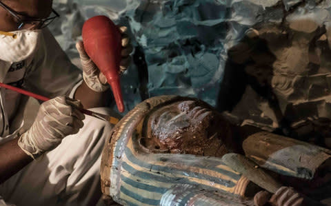 Egyptian archaeologist restoring a wooden sarcophagus at a newly-uncovered ancient tomb for a goldsmith in Luxor - Credit: KHALED DESOUKI/AFP/Getty Images