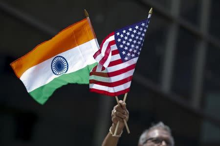 A man holds the flags of India and the U.S. while people take part in the 35th India Day Parade in New York August 16, 2015. REUTERS/Eduardo Munoz/Files