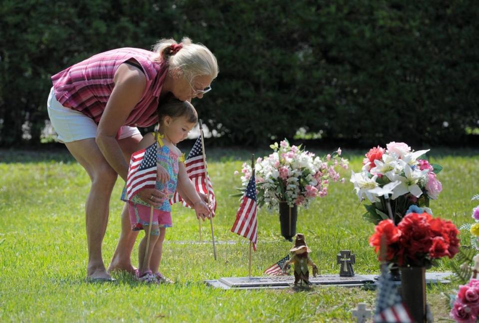 Jean Morone helps her granddaughter Vada Morone place a flag at the gravesite of Vada’s great-grandfather, U.S. Army Veteran and Korean War Veteran Ernest L. Morone, during the “Preparing for Memorial Day” service at Manasota Memorial Park in East Bradenton on Saturday, May 24, 2014.