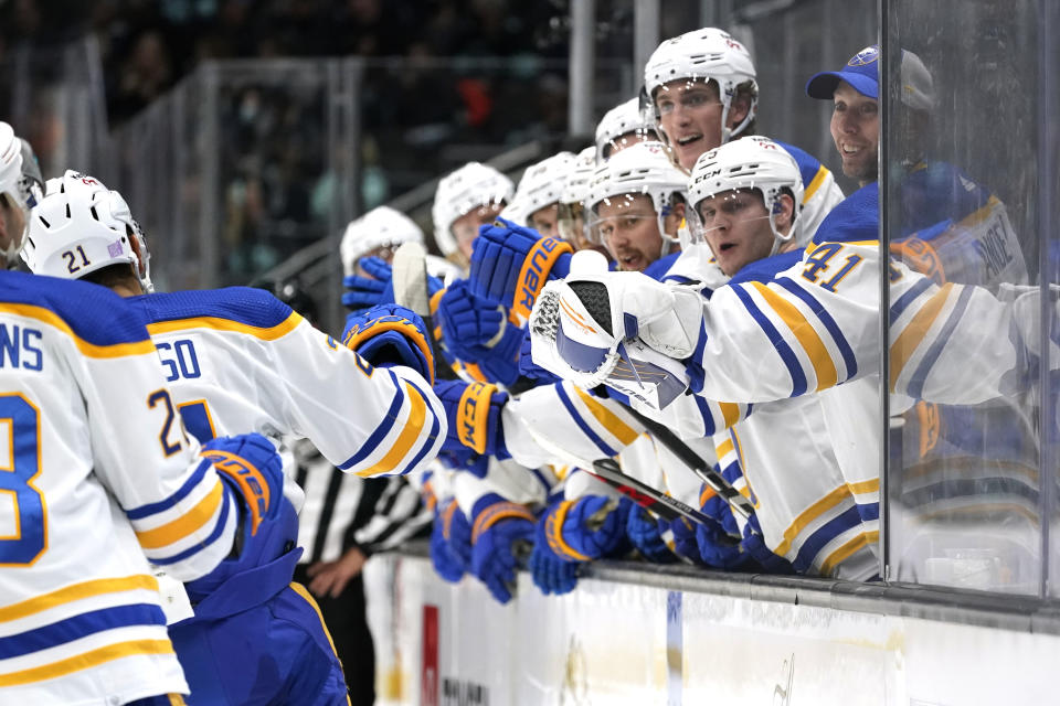 Buffalo Sabres players lean out to congratulate teammates after a score against the Seattle Kraken during the second period of an NHL hockey game Thursday, Nov. 4, 2021, in Seattle. (AP Photo/Elaine Thompson)