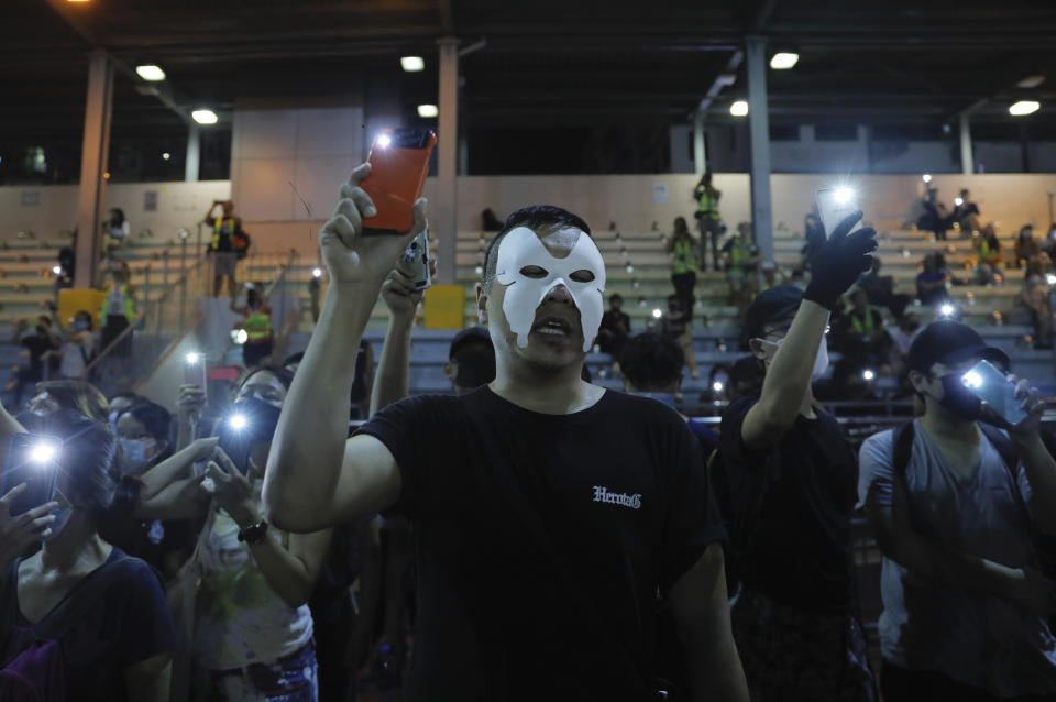 Masked protesters hold up their lit mobile phones as they sing a protest anthem in Hong Kong on Saturday, Oct. 5, 2019. All subway and train services were suspended, lines formed at the cash machines of shuttered banks, and shops were closed as Hong Kong dusted itself off and then started marching again Saturday after another night of rampaging violence decried as "a very dark day" by the territory's embattled leader. (AP Photo/Kin Cheung)
