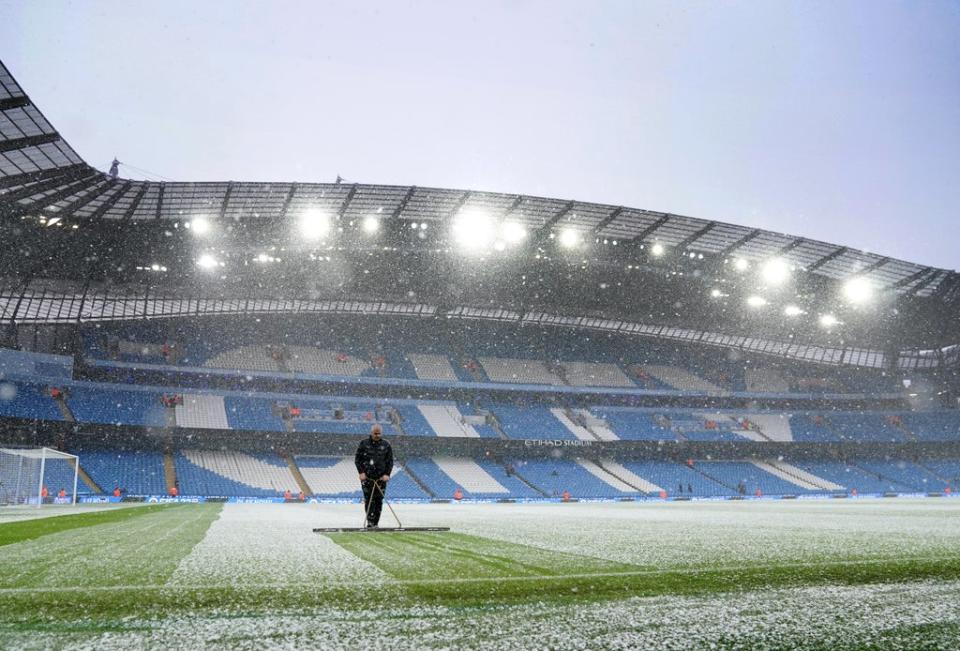 Manchester City head groundskeeper Lee Jackson swept snow off the pitch (Martin Rickett/PA) (PA Wire)