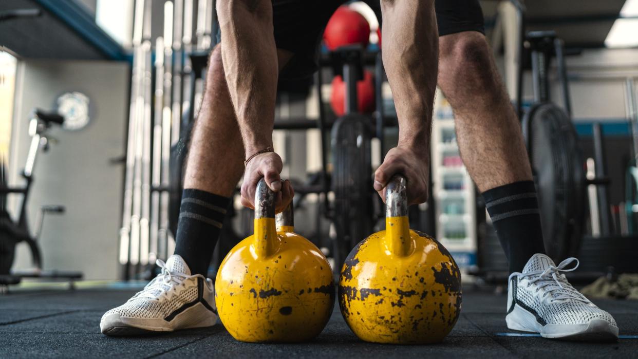  A photo of a man holding two kettlebells. 