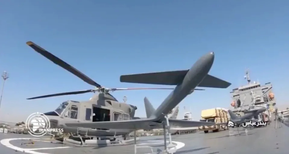 An Ababil-2 drone is displayed in front of a Bell 412 helicopter on the deck of the IRGC <em>Shahid Roudaki</em>. <em>IRAN PRESS SCREENCAP</em>