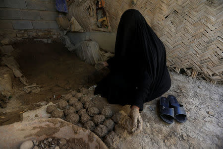 A woman makes ''turba'', a piece of stone or molded clay made of local soil, at her home in Kerbala, Iraq April 2, 2018. REUTERS/Alaa Al-Marjani