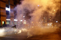 A protester kicks a tear gas canister that was fired towards them by Lebanese riot police during an anti-government protest in Beirut, Lebanon, Wednesday, Dec. 4, 2019. Protesters have been holding demonstrations since Oct. 17 demanding an end to corruption and mismanagement by the political elite that has ruled the country for three decades. (AP Photo/Bilal Hussein)