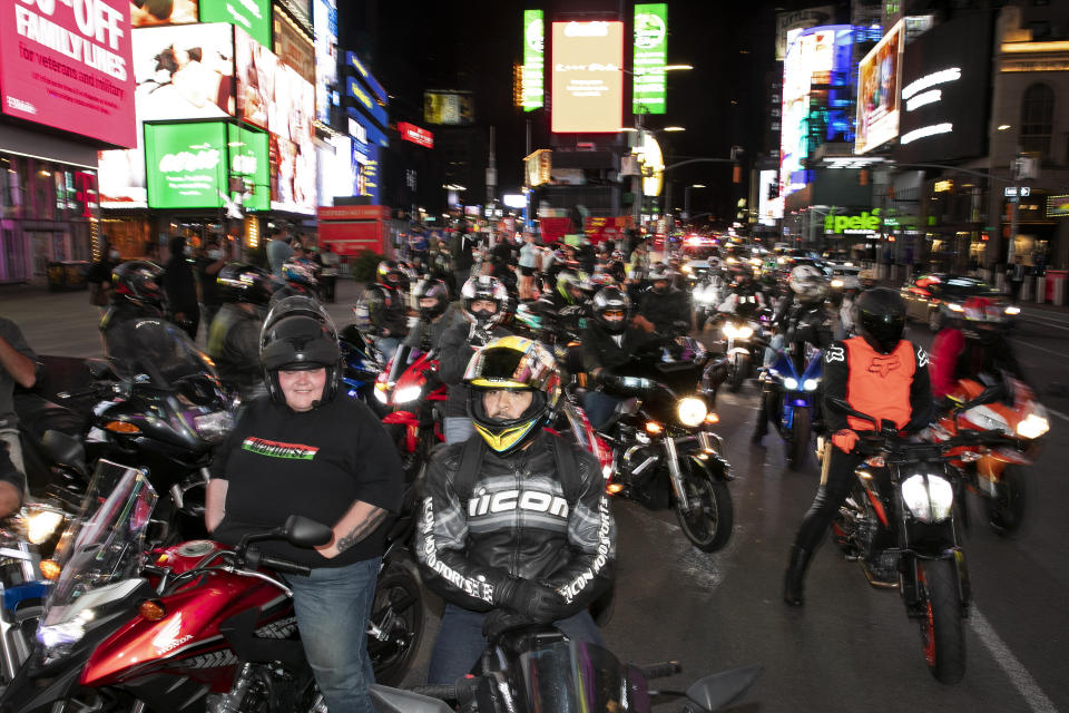 In this Saturday, May 2, 2020 photo, dozens of motorcyclists stop for photos in New York's Times Square during the coronavirus pandemic. Motorcycle enthusiasts normally wouldn't dare rev their engines in Midtown, but now they're eagerly driving into the city to take photos and show off for sparse crowds walking through the commercial hub. (AP Photo/Mark Lennihan)