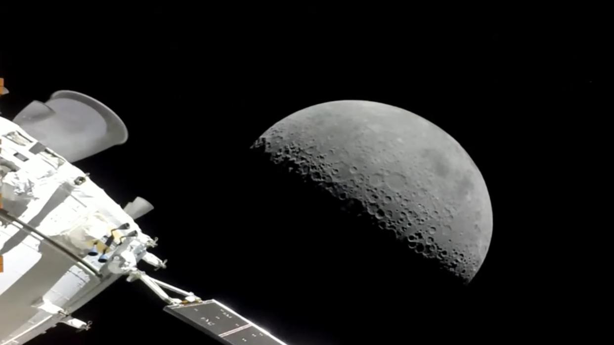  Back end of a spacecraft with engine and solar panels in deep space. behind is the half-illuminated moon. 